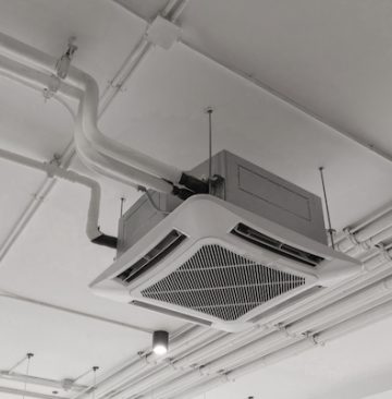 Modern white ceiling mounted cassette type air conditioner in office building system work. Ventilation compressor.