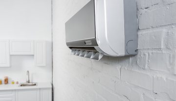 close-up shot of air conditioner hanging on white brick wall